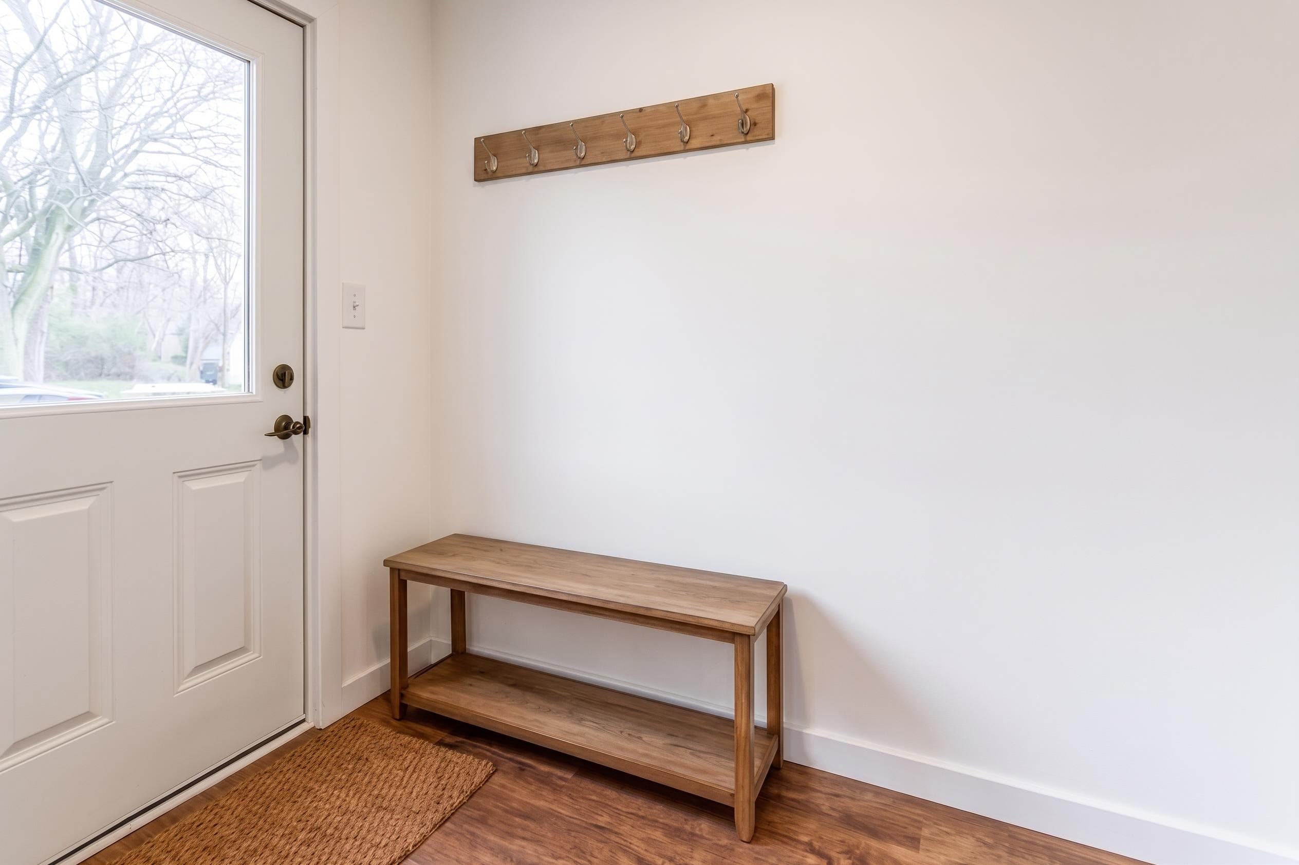 Bright entryway in a Keyhold home with a wood bench and coat hooks